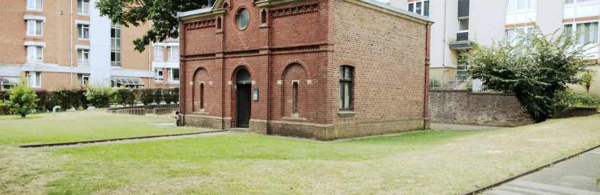 Das backsteinernde ehemalige Kutscherhaus mitten auf einer Wiese in einem Hinterhof